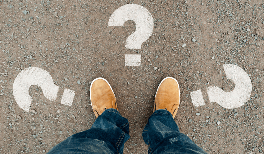 Stock image looking down at feet with question marks in different directions