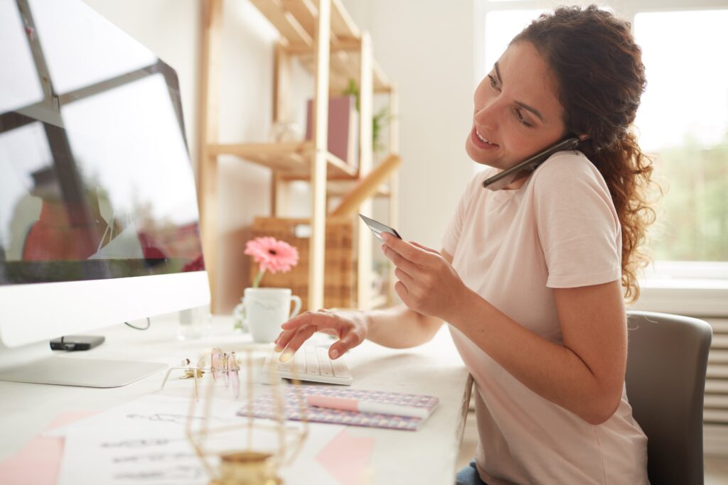 Stock image of a woman working on the computer with a debit card in hand