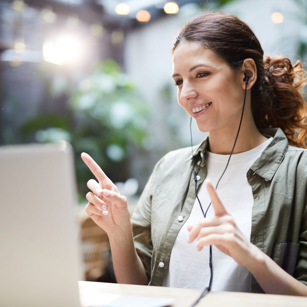 photo of woman using computer with headphones in ears