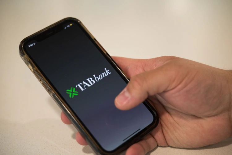 Stock phone in hand opening the TAB app